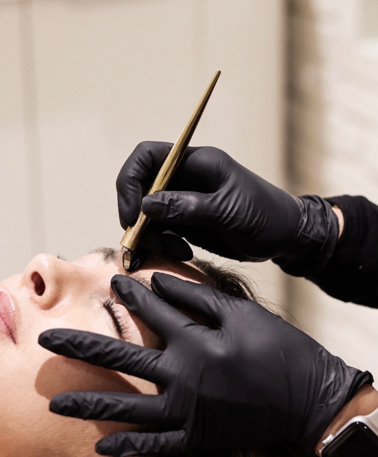 Close-up of Jade's hands creating microblading strokes with a gold tool